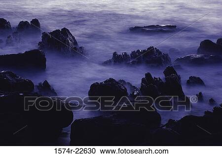 Stock Image - Ocean and rocks in mist. Fotosearch