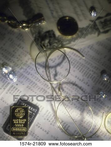 Stock Photo - Pair of eyeglasses with gold biscuits and coins. Fotosearch