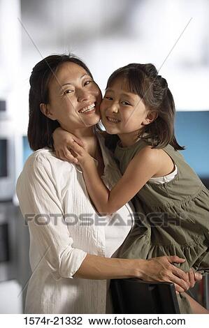 Stock Image - Portrait of a mid adult woman hugging her daughter. Fotosearch