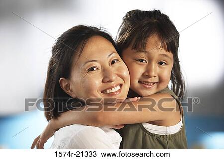Stock Image - Portrait of a mid adult woman hugging her daughter. Fotosearch
