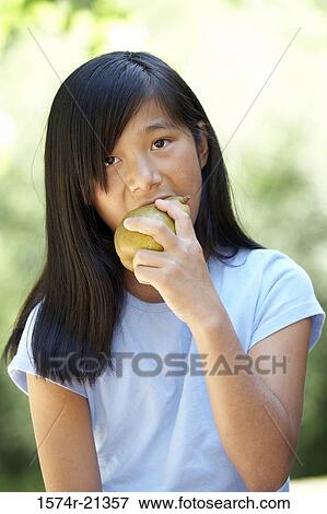 Portrait of a teenage girl eating a pear View Large Photo Image Stock Photo - Portrait of a teenage girl eating a pear. Fotosearch