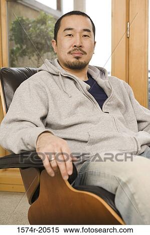 Portrait of a young man sitting in an armchair View Large Photo Image Stock Photography - Portrait of a young man sitting in an armchair. Fotosearch