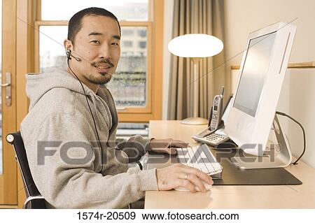 Portrait of a young man using a computer View Large Photo Image Stock Photo - Portrait of a young man using a computer. Fotosearch