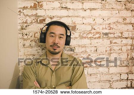Stock Photo - Portrait of a young man wearing headphones and listening to music. Fotosearch