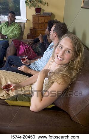 Portrait of a young woman sitting with her friends at a party View Large Photo Image Stock Image - Portrait of a young woman sitting with her friends at a party. Fotosearch