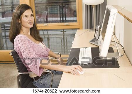 Portrait of a young woman using a computer View Large Photo Image Stock Image - Portrait of a young woman using a computer. Fotosearch