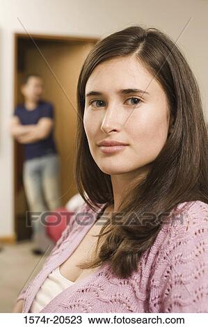 Portrait of a young woman with a young man leaning against a wall in the background View Large Photo Image Stock Image - Portrait of a young woman with a young man leaning against a wall in the background. Fotosearch