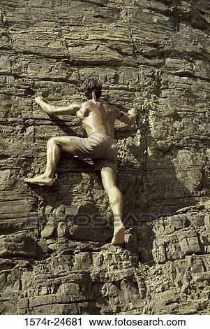 Rear view of a young man climbing up a rock face View Large Photo Image Stock Image - Rear view of a young man climbing up a rock face. Fotosearch