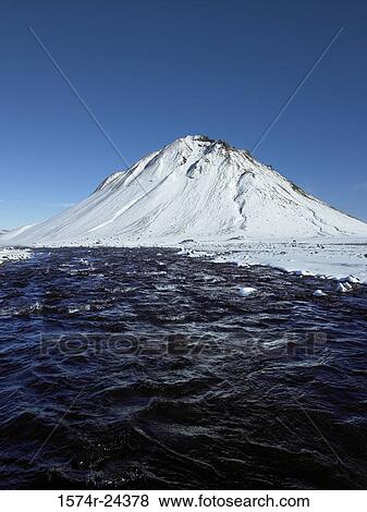 Stock Photo - River flowing through a snow covered landscape near a mountain, Brennivinskvisl River, Mount Maelifell, Iceland. Fotosearch