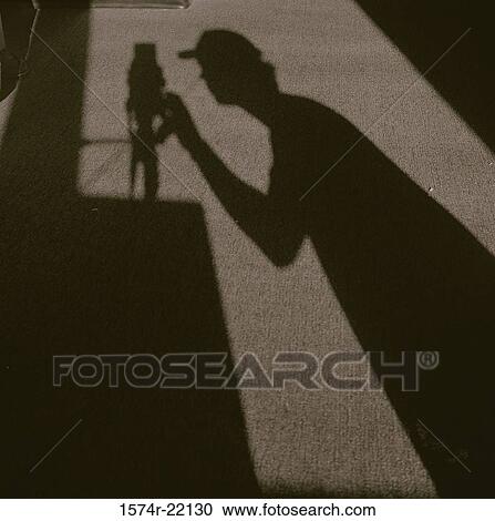 Shadow of a photographer operating a camera View Large Photo Image Stock Image - Shadow of a photographer operating a camera. Fotosearch