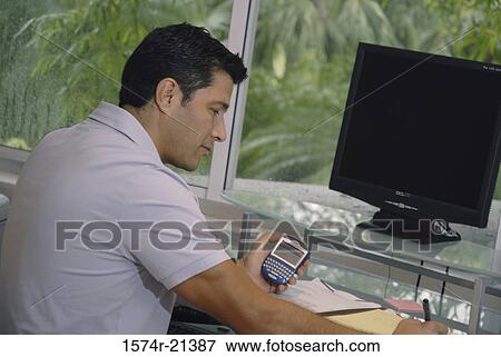 Stock Photo - Side profile of a businessman sitting in front of a computer. Fotosearch