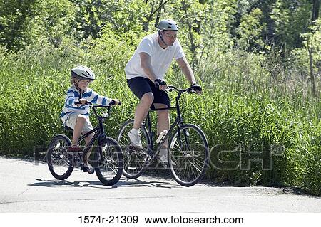 Side profile of a mid adult man cycling with his son View Large Photo Image Stock Photo - Side profile of a mid adult man cycling with his son. Fotosearch