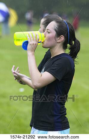 Stock Image - Side profile of a young woman drinking water. Fotosearch