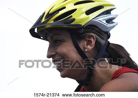 Picture - Side profile of a young woman wearing a cycling helmet. Fotosearch