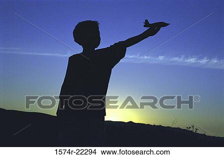 Silhouette of a boy holding out an airplane View Large Photo Image Picture - Silhouette of a boy holding out an airplane. Fotosearch