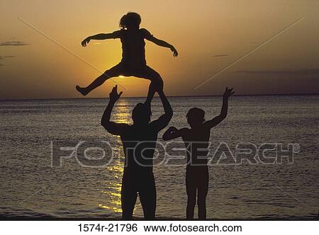 Silhouette of a family playing on a beach View Large Photo Image Stock Photograph - Silhouette of a family playing on a beach. Fotosearch