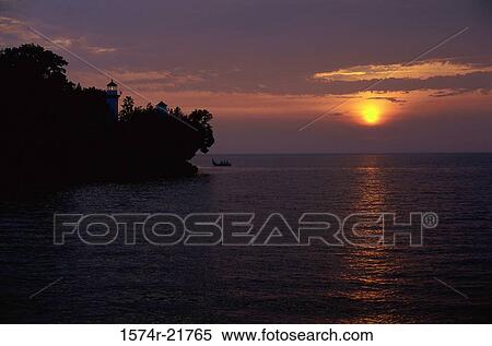 Silhouette of a lighthouse on a cliff near the ocean during sunset View Large Photo Image Stock Photography - Silhouette of a lighthouse on a cliff near the ocean during sunset. Fotosearch