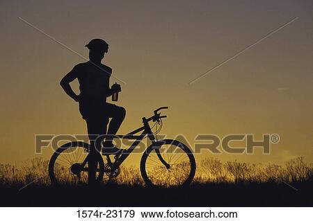 Silhouette of a man sitting on a bicycle View Large Photo Image Stock Photo - Silhouette of a man sitting on a bicycle. Fotosearch