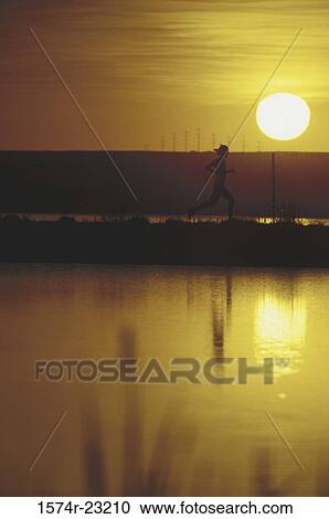 Stock Image - Silhouette of a young woman jogging, Boulder Valley, Ranch Open Space, Boulder, Colorado, USA. Fotosearch