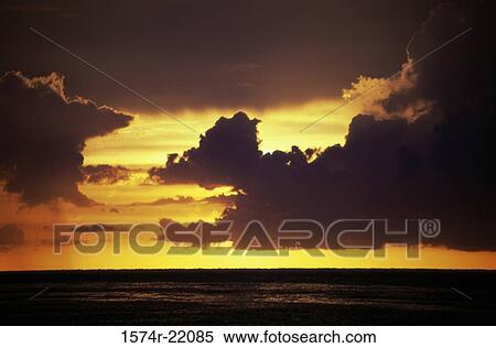 Stock Photography - Sunset in a cloudy sky over the ocean. Fotosearch