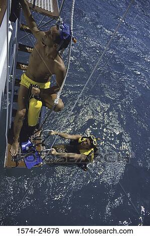 Two young men climbing up a boat's ladder View Large Photo Image Stock Photo - Two young men climbing up a boat's ladder. Fotosearch