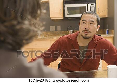 Two young men sitting at a coffee table View Large Photo Image Stock Photography - Two young men sitting at a coffee table. Fotosearch
