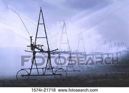 Water sprinklers irrigating a field of crops View Large Photo Image Stock Photo - Water sprinklers irrigating a field of crops. Fotosearch