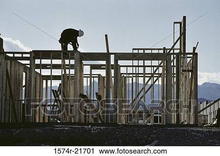 Stock Image - Worker working on the roof of a house under construction. Fotosearch