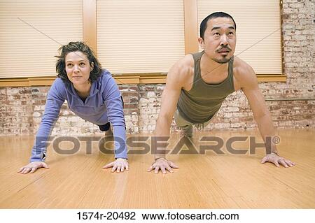 Stock Image - Young couple doing push-ups. Fotosearch