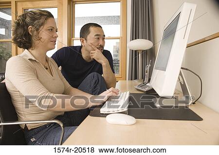 Young couple sitting in front of a computer View Large Photo Image Stock Photo - Young couple sitting in front of a computer. Fotosearch