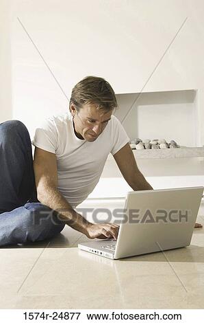 Stock Photo - Young man using a laptop on the floor. Fotosearch