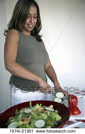 Young woman cutting slices of cucumber on a cutting board View Large Photo Image Stock Image - Young woman cutting slices of cucumber on a cutting board. Fotosearch