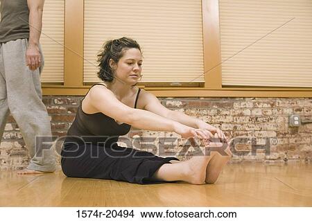 Picture - Young woman exercising with a young man walking behind her. Fotosearch