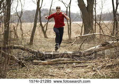 Young woman leaping over a fallen tree View Large Photo Image Stock Photography - Young woman leaping over a fallen tree. Fotosearch
