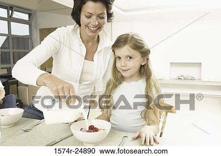 Stock Image - Young woman serving breakfast to her daughter. Fotosearch