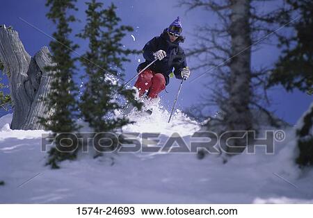 Stock Image - Young woman skiing down a hill. Fotosearch