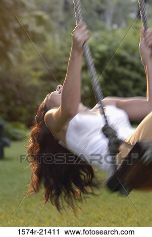 Young woman swinging on a rope swing View Large Photo Image Stock Image - Young woman swinging on a rope swing. Fotosearch