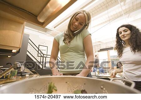Young woman talking on a cordless phone with another young woman standing beside her View Large Photo Image Stock Photo - Young woman talking on a cordless phone with another young woman standing beside her. Fotosearch