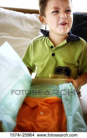 Boy holding a gift and making a face View Large Photo Image Picture - Boy holding a gift and making a face. Fotosearch