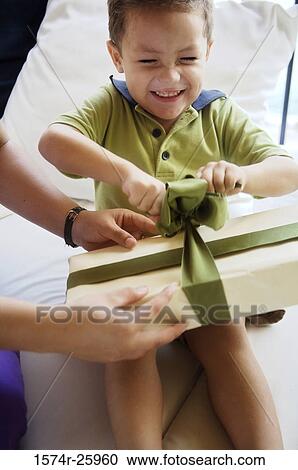 Boy opening a gift with his eyes closed and smiling View Large Photo Image Stock Image - Boy opening a gift with his eyes closed and smiling. Fotosearch