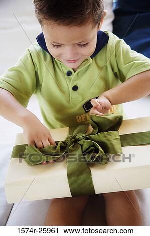 Boy sitting on the bed and opening a gift View Large Photo Image Stock Image - Boy sitting on the bed and opening a gift. Fotosearch