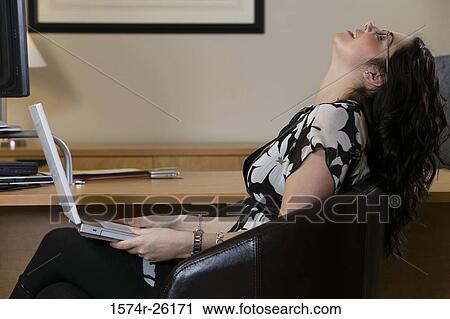 Businesswoman sitting and holding a laptop View Large Photo Image Stock Image - Businesswoman sitting and holding a laptop. Fotosearch