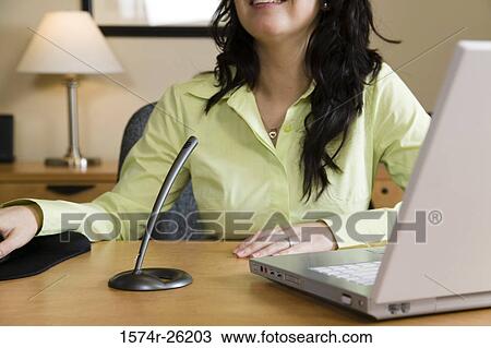 Businesswoman sitting in front of a laptop View Large Photo Image Stock Image - Businesswoman sitting in front of a laptop. Fotosearch