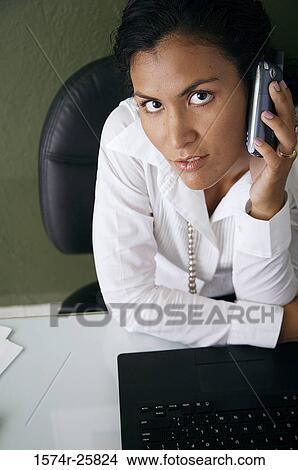 Businesswoman talking on a mobile phone in an office View Large Photo Image Picture - Businesswoman talking on a mobile phone in an office. Fotosearch