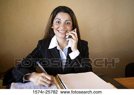 Businesswoman talking on a mobile phone in an office View Large Photo Image Stock Image - Businesswoman talking on a mobile phone in an office. Fotosearch
