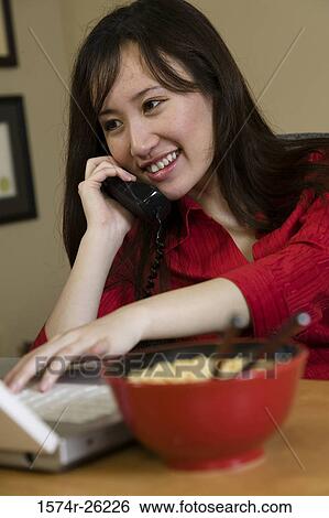 Businesswoman talking on the phone and using a laptop View Large Photo Image Stock Photograph - Businesswoman talking on the phone and using a laptop. Fotosearch