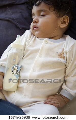 Close-up of a baby sleeping with a milk bottle View Large Photo Image Stock Photograph - Close-up of a baby sleeping with a milk bottle. Fotosearch