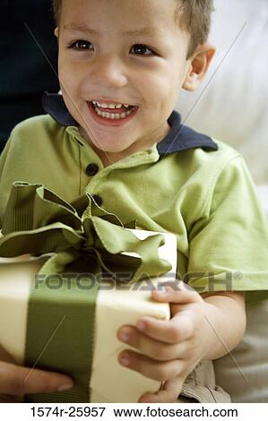 Close-up of a boy holding a gift and smiling View Large Photo Image Stock Photo - Close-up of a boy holding a gift and smiling. Fotosearch