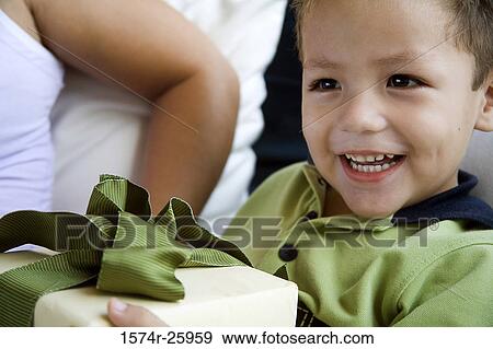 Close-up of a boy holding a gift and smiling View Large Photo Image Stock Photo - Close-up of a boy holding a gift and smiling. Fotosearch