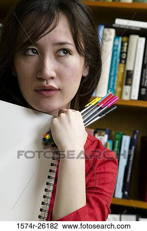 Stock Image - Close-up of a businesswoman holding a drawing pad and pens. Fotosearch